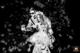 A black and white wedding photograph depicts a bride and groom in Punta Barranca, Argentina, dancing. They hold bubble guns, blowing bubbles as they celebrate in Rosario, Santa Fe, Argentina.